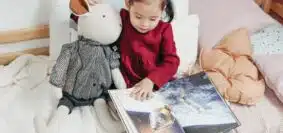 une petite fille dans son lit lisant un magazine