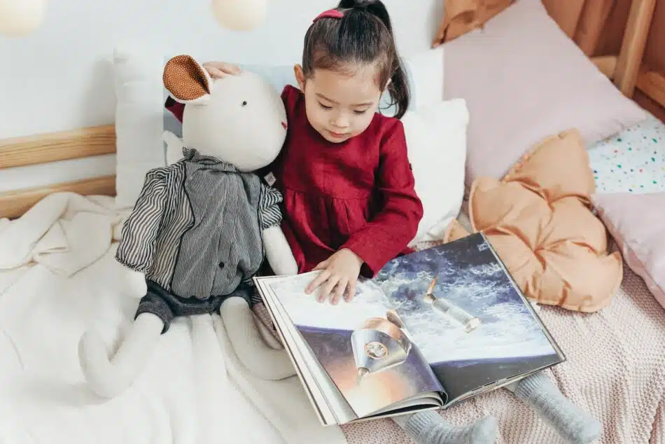une petite fille dans son lit lisant un magazine