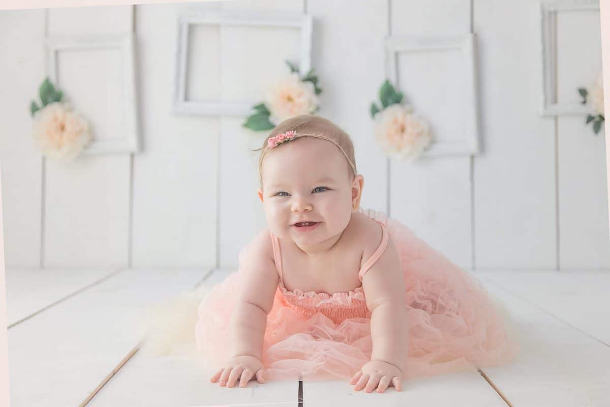 Qu'offrir à un bébé pour un baptême ? Bébé en robe rose sur un fond blanc